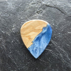 Gitarrenplektrum aus Edelholz und Blau-Weißer Kunstharz in Handarbeit hergestellt, auf einem Schieferstein liegend