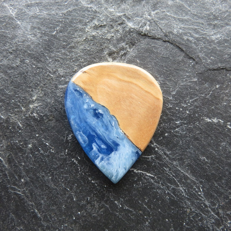 Gitarrenplektrum aus  Olivenholz und hellblauem Epoxidharz in dem weiße Wolkenartige Streifen verlaufen