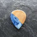 Gitarrenplektrum aus  Olivenholz und hellblauem Epoxidharz in dem weiße Wolkenartige Streifen verlaufen